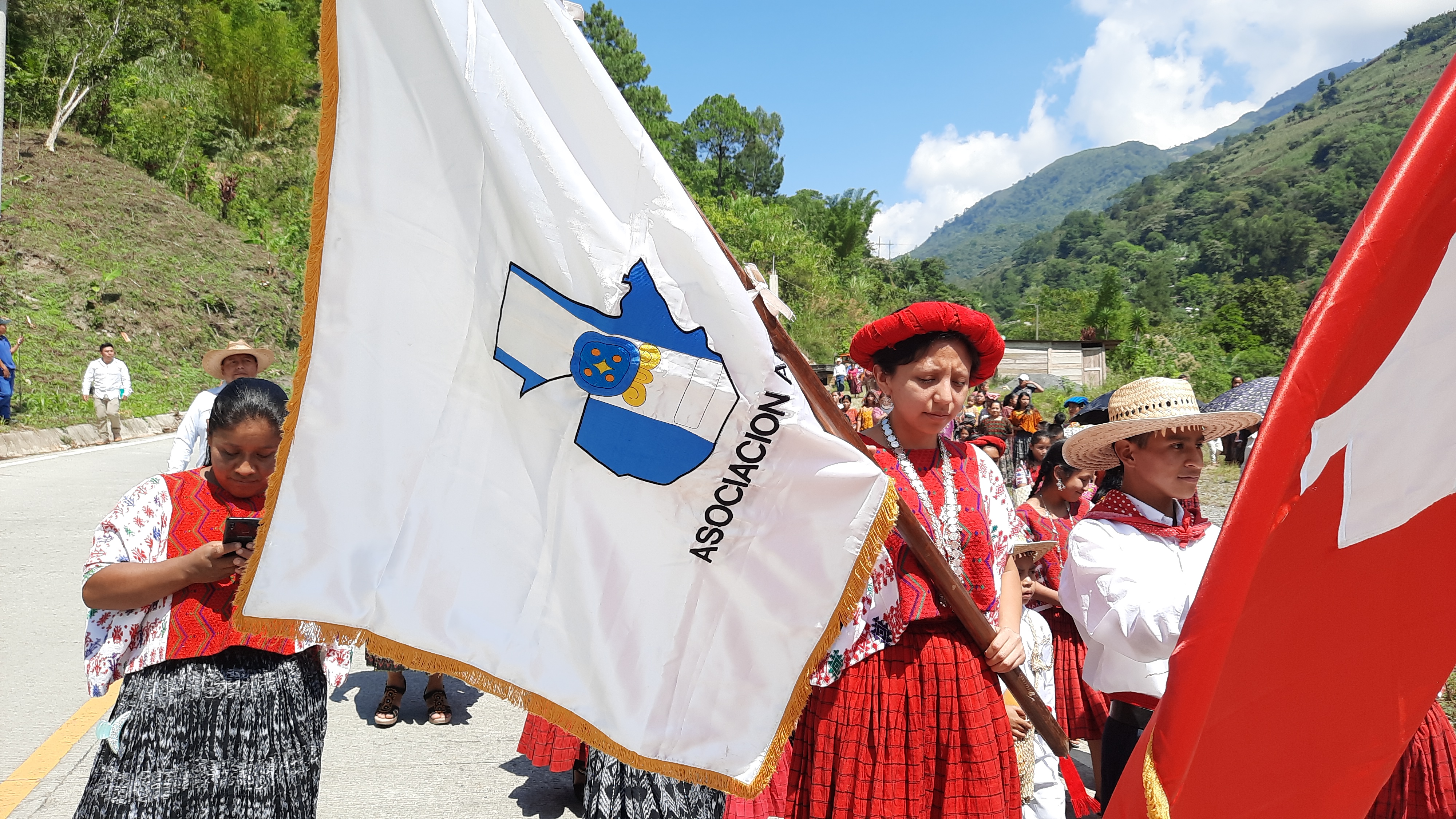 Integrantes de una comunidad portan la bandera de ADICAY durante una actividad comunitaria