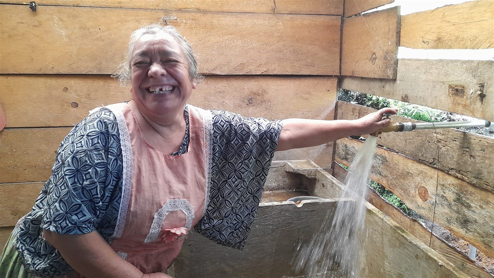 Woman using water from a community system supported by ADICAY
